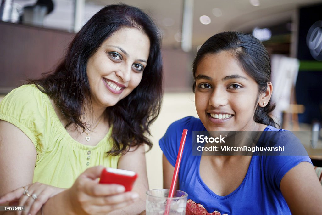 Indiana alegre Mãe e filha lendo o envio de SMS na Cafeteria - Foto de stock de 14-15 Anos royalty-free