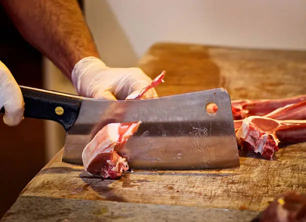 Butcher cutting raw meat