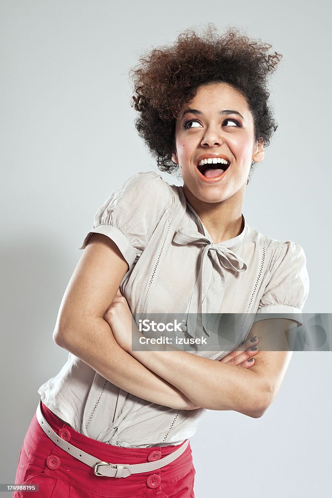 Cute Teen Girl Portrait of happy teen afro girl wearing red shorts, standing against grey background with crossed arms. Studio Shot Stock Photo