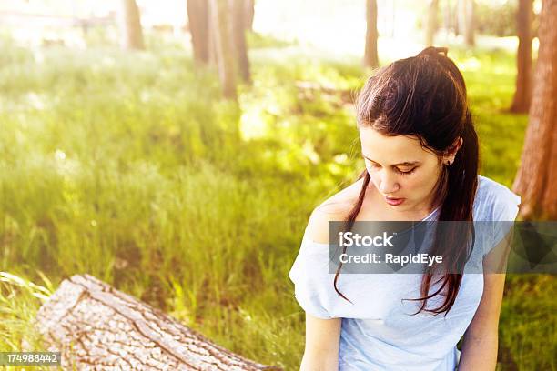 Bonita Jovem Brunette Fica Na Floresta Olhar Para Baixo - Fotografias de stock e mais imagens de 20-29 Anos