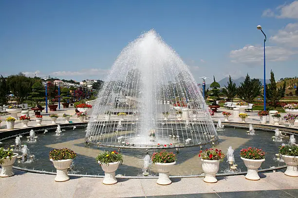 "Beautiful circular fountain, surrounded by flowering plants in Dalat flower gardens, in Vietnam's Central Highlands."