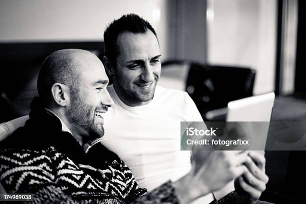 Gay Couple Sitting Arm In Arm And Using Digital Tabletamorous Couple Using Digital Tablet Stock Photo - Download Image Now