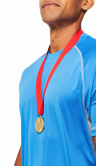 Midsection of male athlete in blue t-shirt wearing gold medal. Vertical shot. Isolated on white.