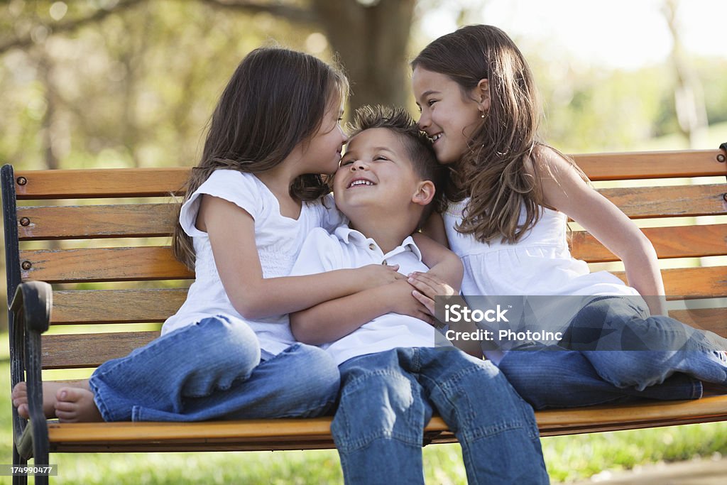 Petites sœurs s'enlacer frère sur banc - Photo de 2-3 ans libre de droits