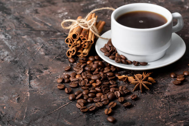 Coffee beans and cinnamon on a background of burlap. Roasted coffee beans background close up. Coffee beans pile from top with copy space for text. Seasoning. Spice. Cinnamon. Badian. Coffee house.