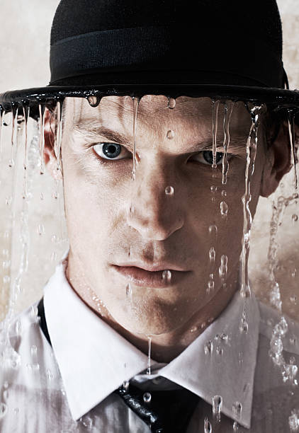 Feeling under the weather Closeup portrait of a handsome young businessman wearing hat while standing in a downpour of water soaked suit stock pictures, royalty-free photos & images
