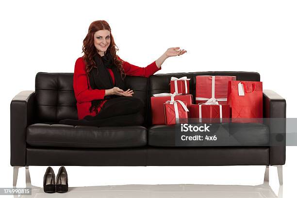 Frau Sitzt Auf Einem Sofa Mit Geschenken Stockfoto und mehr Bilder von Attraktive Frau - Attraktive Frau, Band, Blick in die Kamera