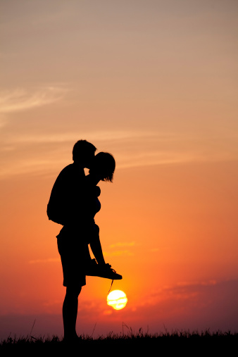 A silhouette of a woman giving a child a piggyback ride. Parenting concept. Family. Verticl colour image.