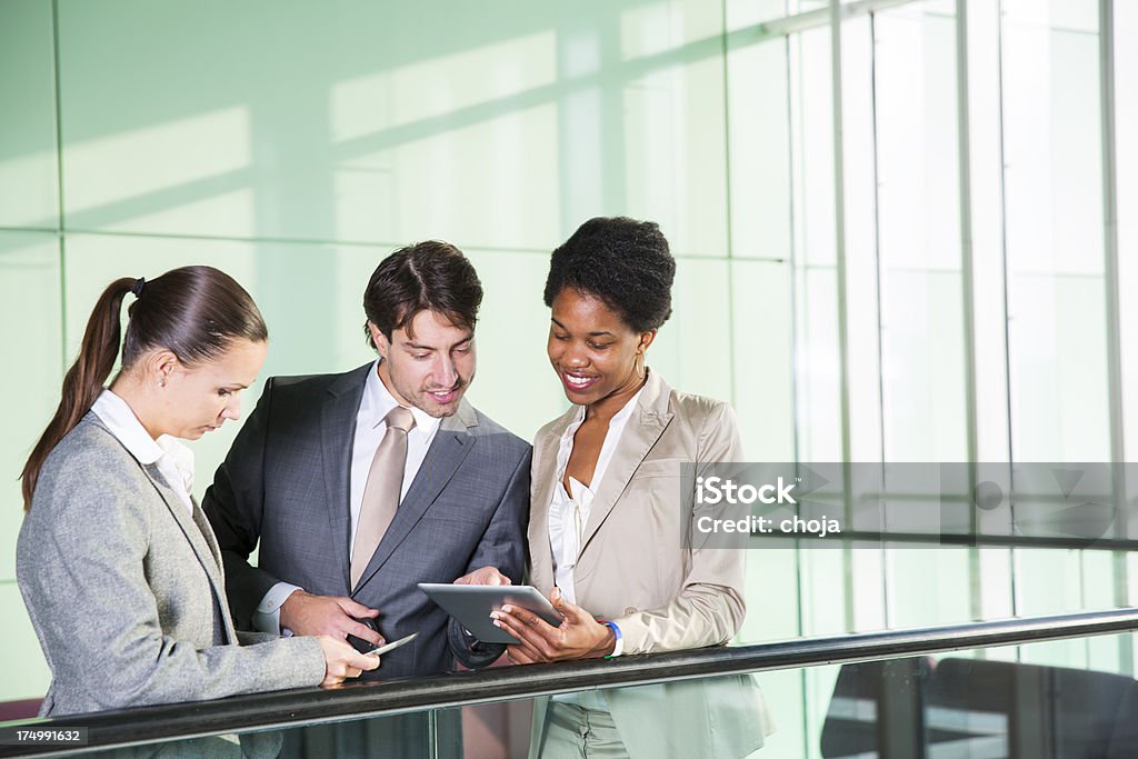 Empresário e duas belas garotas verificando dados no tablet digital - Foto de stock de Alegria royalty-free