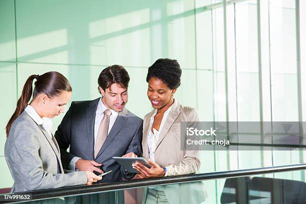 Foto de Empresário E Duas Belas Garotas Verificando Dados No Tablet Digital e mais fotos de stock de Alegria