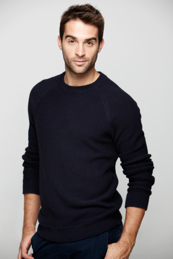 Portrait of mid adult man in blue sweater against grey background