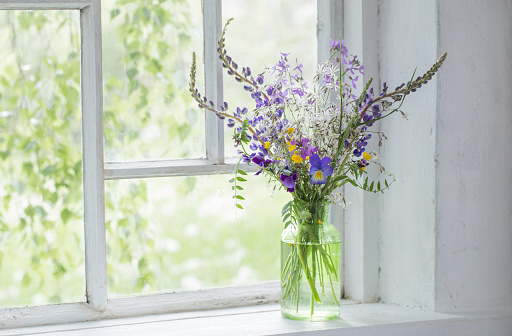 Sweet pea flowers in a jug on an old window sill with a garden background