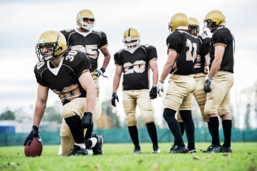 American football player holding the ball in his hands in front of the camera. Concept American football, motivation, black background.