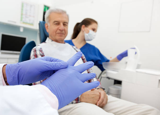 dentista mettendo su guanti chirurgici - hhpm26 foto e immagini stock
