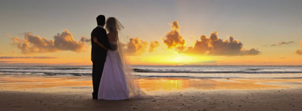 istock Bride and groom looking towards sunset on beach 174993224