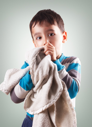 Three years old child holding his blanket and sucking his thumb.