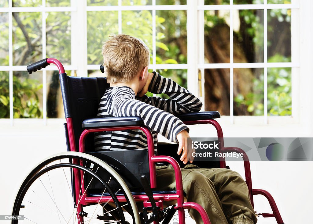 J'aimerais aussi pouvoir jouer ! Petit garçon en regardant le jardin, pour personnes à mobilité réduite - Photo de 8-9 ans libre de droits