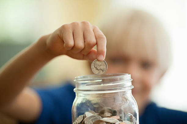 Boy Saving Coins In Money Jar