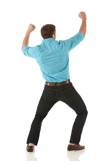 Rear view of a man standing with his arms raised Rear view of a man standing with his arms raised legs apart stock pictures, royalty-free photos & images