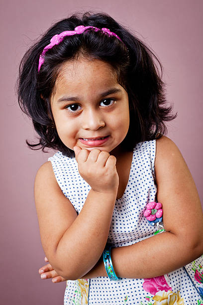 Portrait of Cheerful Indian Girl With Hand On Chin Image Available - Download Image Now - 2-3 years old, Headband, Portrait -