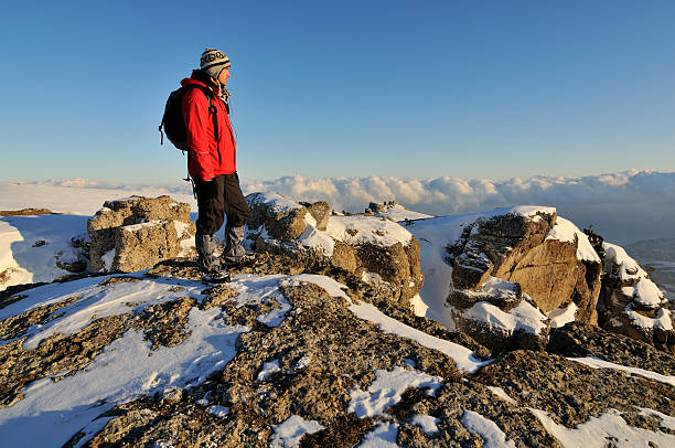 Backpacker standing on a rock in winter mountains stock photo