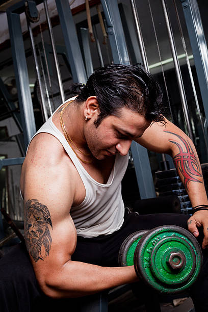 istock Strong Asian Indian Man Using Dumbbell Exercising in Gym 174995561
