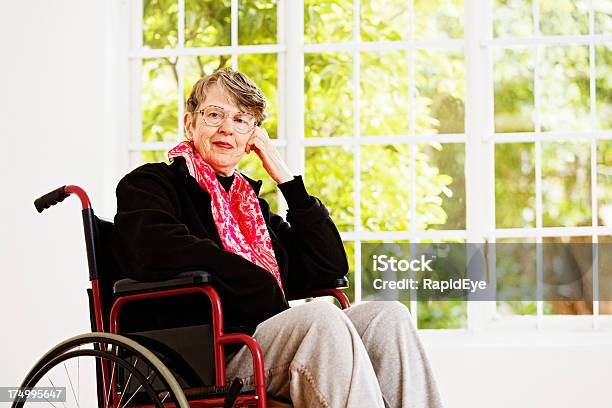 Feliz Idade Mulher Em Cadeira De Rodas Sorrisos Pela Janela - Fotografias de stock e mais imagens de 60-69 Anos