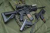 Tactical firearms on camouflage background, rifles and pistols