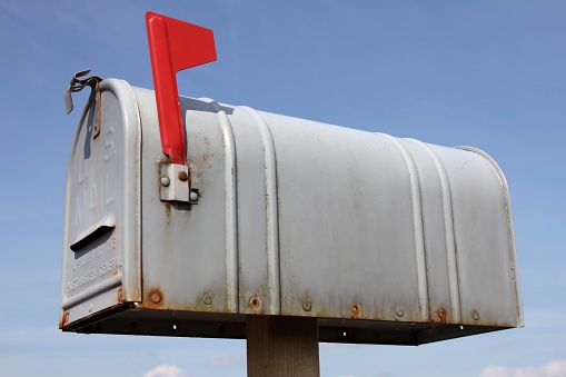 weathered American mailbox against blue sky