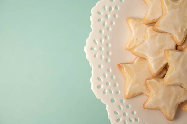 Star holiday sugar cookies stacked on a pretty white cake plate. Birds eye view with copy space and a light blue background.