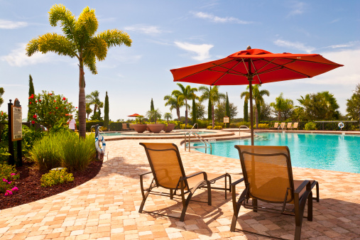 Beautiful tropical garden with large poolside and spa in Florida. Loungers under the parasol inviting you to relax.