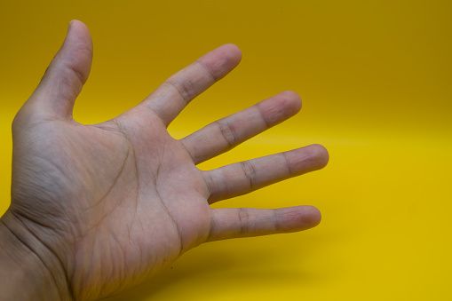 Man giving high five on yellow background, closeup of hand