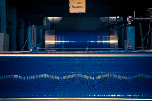 Denim Textile Industry - Rope Dyeing Machine Blue Dyed thread getting wrapped on spools for weaving looms after getting dyed on rope dyeing machine.Variation visible as thread color changes in rope dyeing machine for making denim fabric. dye stock pictures, royalty-free photos & images