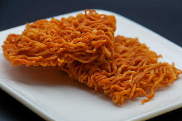 dry noodle snack ready to eat dry noodle snack ready to eat, on a plate on a black background dissert stock pictures, royalty-free photos & images