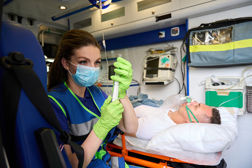 Nurse and doctor using medical ventilator on female patient while cardiopulmonary resuscitation in ICU and monitoring health. CPR in ICU