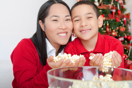 Happy asian mother and son stringing popcorn