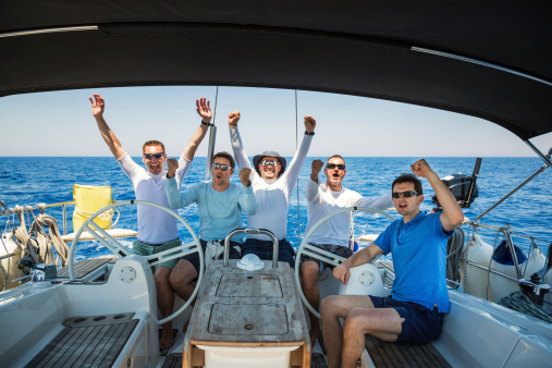 Happy sailing crew of 5 people on sailboat. 