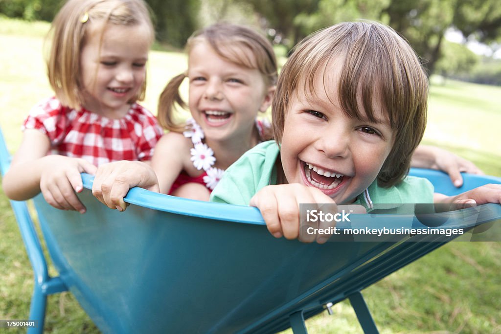 Tres niños en la carretilla de estar - Foto de stock de Carretilla libre de derechos