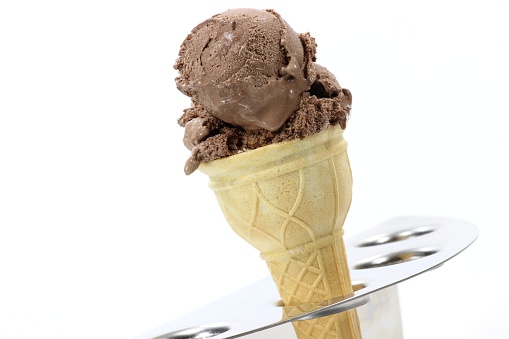 chocolate ice cream in sugar cone against white background