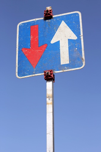 Crossroads Road Sign, Two Arrow on blue sky background. Two way blank road sign with copy space. Two arrows on a pole pointing in different directions