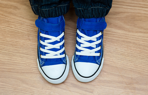 Modern youth sneakers on the feet of a young boy at home