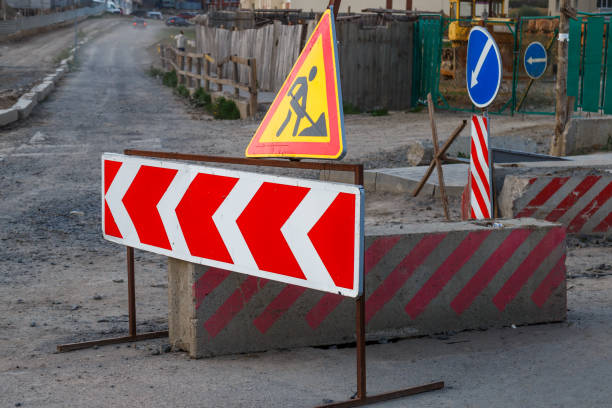 istock Work continues. Road works, road signs. Men at work. Some signage signs for work in progress on a city street. Barriers and road signs. Silhouette of a worker at work. 1750083703