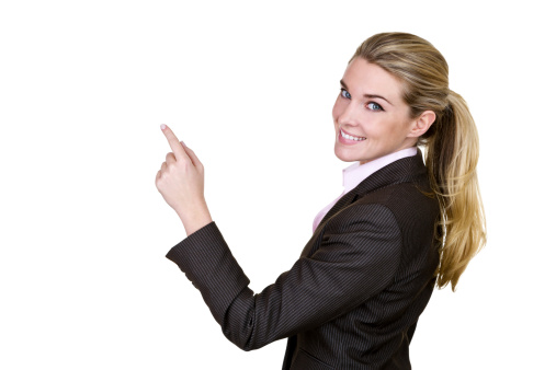 Cheerful businesswoman wearing a suit and pointing to copy space while being isolated on white background 