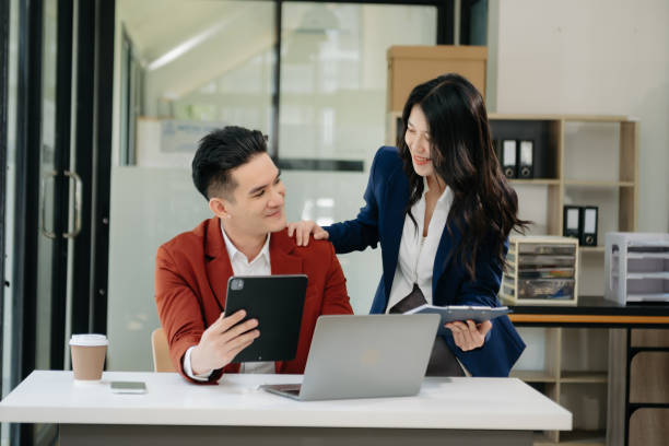 istock Asian business colleague business presents and explains and using laptop and tablet. Teamwork, financial marketing team,   while sitting in modern office 1750148585