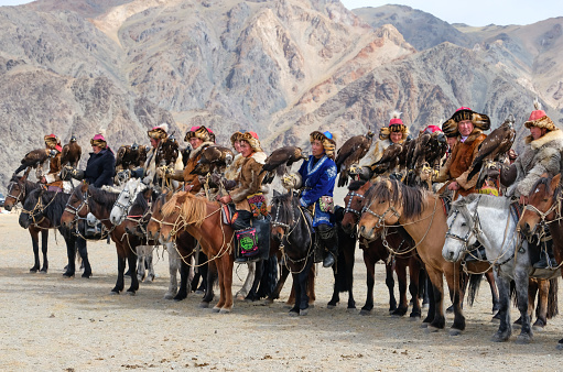 Eagle hunters, on their horses, gathering at the opening ceremony of the Sagsai Golden Eagle Festival, held on 17th-18th September 2023, near the small town of Sagsai, in the Bayan-Ulgii province of Western Mongolia. Set in the Altai Mountain range, the nomadic eagle hunters, dressed in traditional fur and embroidered clothing, gather to compete with their eagles, in various competitions that show the skill and bond between the hunter and their eagle.