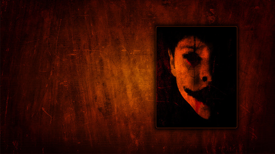 Horizontal portrait of a child, with spooky make up and blank hollow ghost like eyes face, covered with spider web or cobweb scars over wood texture scratched rough rustic dark brown halloween backgrounds. Apt for use as posters, backdrops, banners, greeting cards for Halloween Day. There is  ample copy space for text.