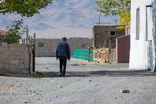 16th September 2023: The rear view of a man walking along a quiet back street of the small town of Sagsai in the Bayan-Ölgii region of the Altai Mountains in Western Mongolia.