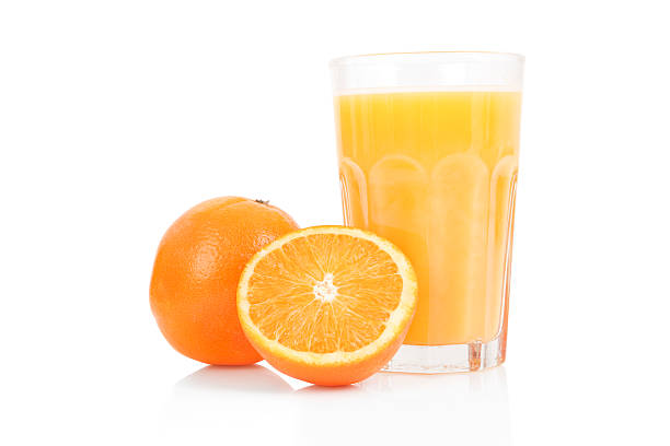 Fresh orange juice in glass cup next to a sliced orange