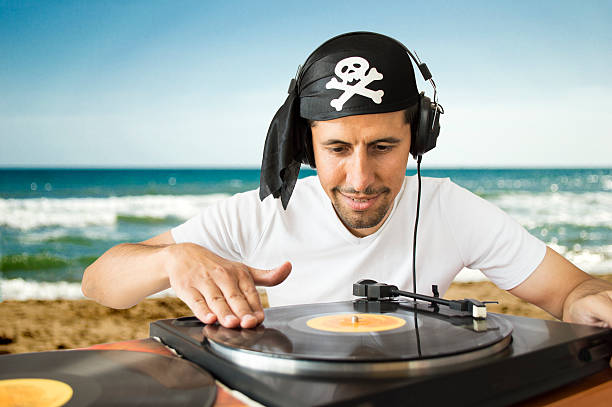 DJ mixing  pirate on the beach DJ mixing vinyl record on a  turntable with a pirate costume on the  beach dubstep photos stock pictures, royalty-free photos & images
