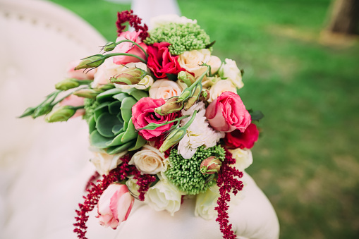 Beautiful wedding bouquet lying outdoors on a green background